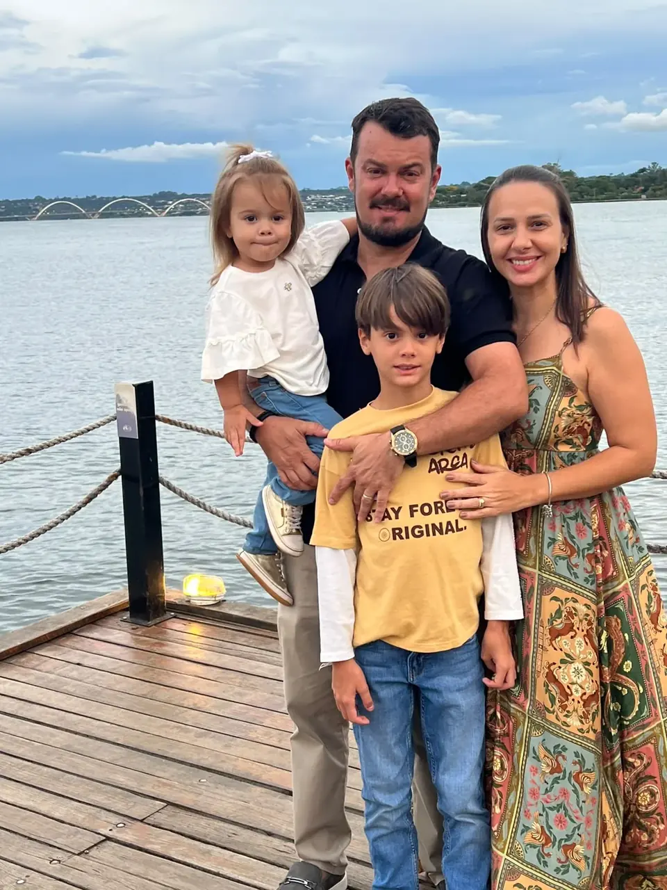 Família sorrindo junto ao lago em Palmas, representando as famílias protegidas pela AS Seguros e Consórcios.